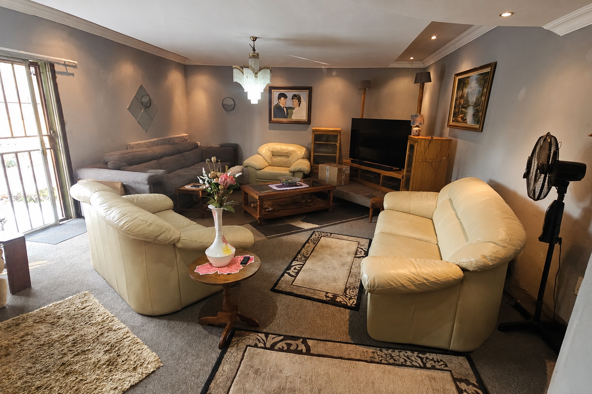 Spacious living room featuring recessed lighting, a decorative chandelier, and direct access to an outdoor area through a sliding glass door with security gate.