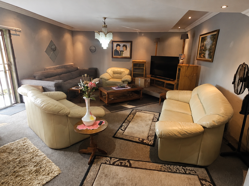 Spacious living room featuring recessed lighting, a decorative chandelier, and direct access to an outdoor area through a sliding glass door with security gate.