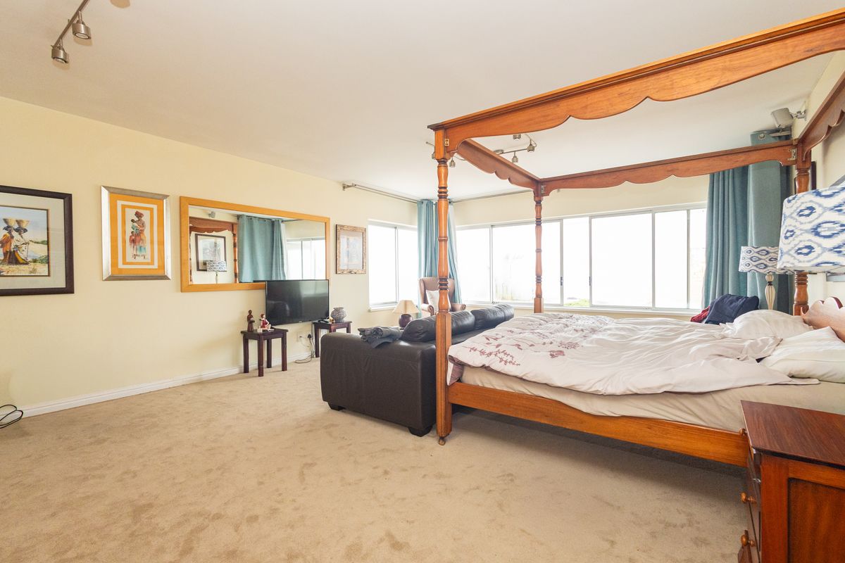 Spacious bedroom featuring large sliding windows, neutral carpeting, and track lighting, offering a comfortable and well-lit living space.