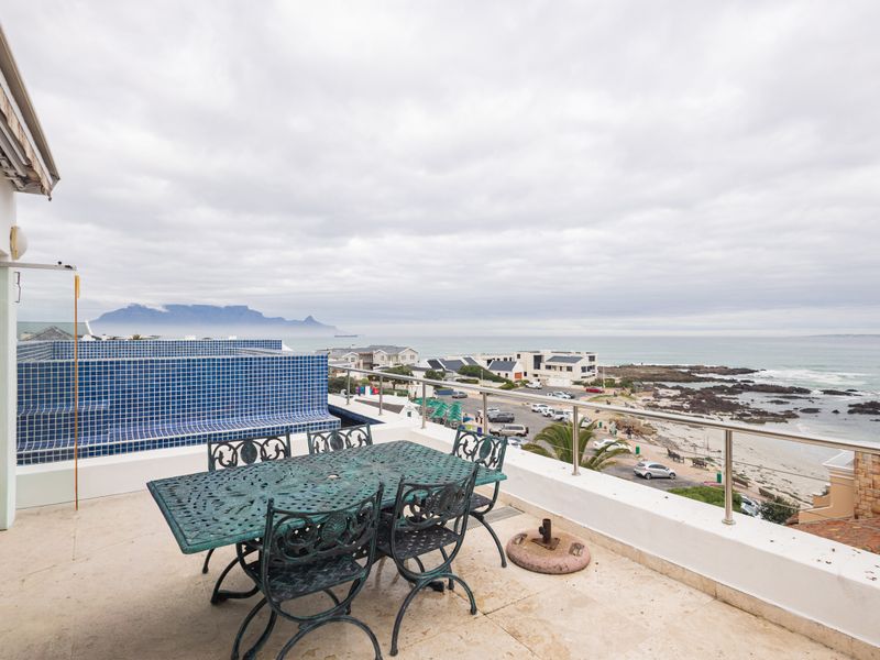 Spacious balcony featuring a stainless steel balustrade and tiled flooring, offering panoramic coastal and mountain views.