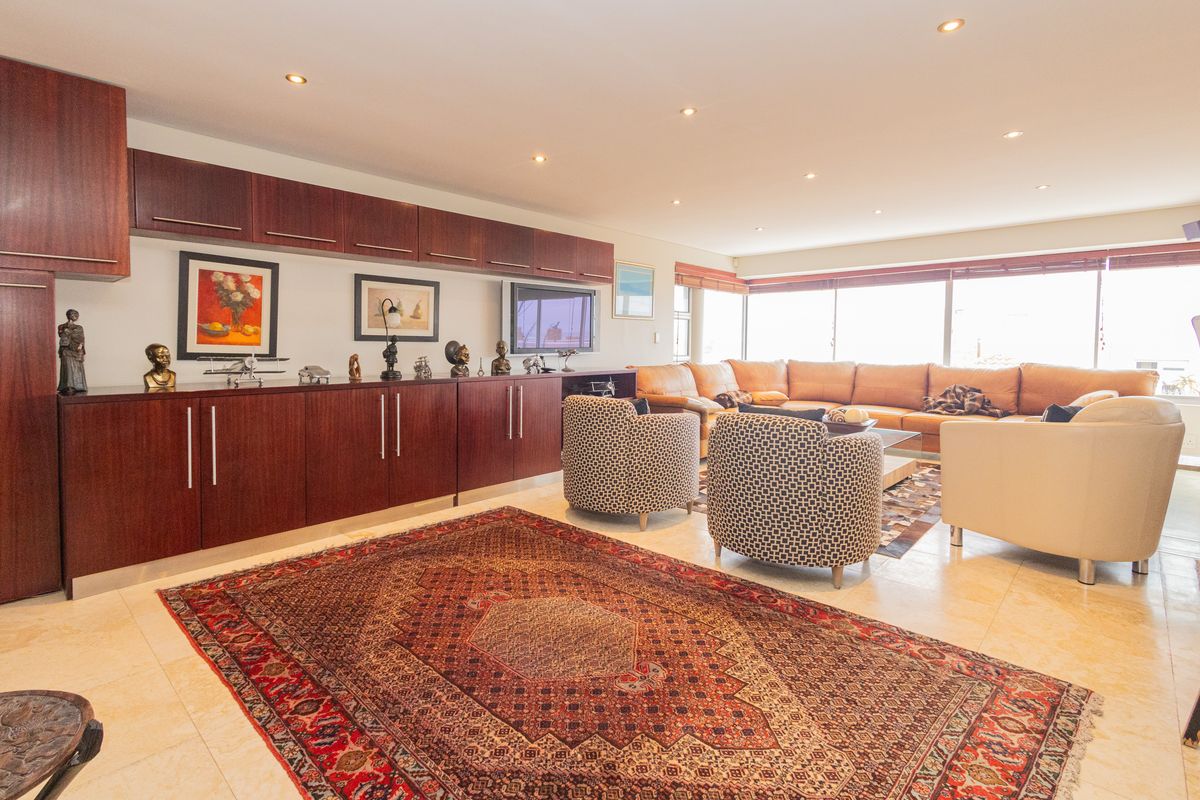Spacious living room featuring extensive built-in dark wood cabinetry, polished tile flooring, and large windows providing ample natural light.