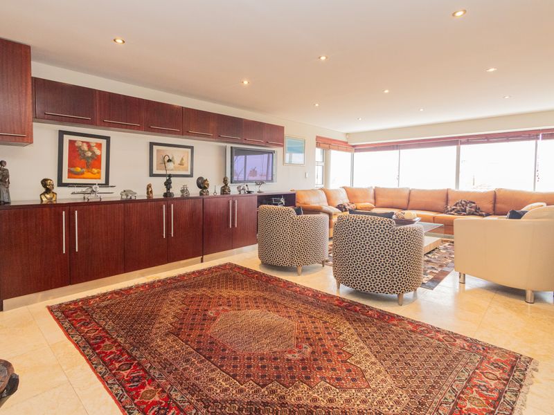 Spacious living room featuring extensive built-in dark wood cabinetry, polished tile flooring, and large windows providing ample natural light.