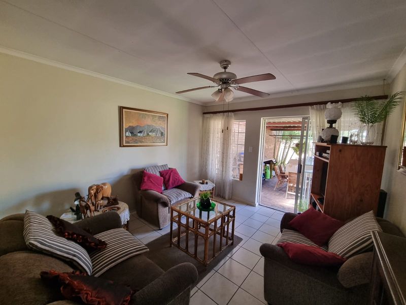 A comfortable living room featuring tiled flooring, a ceiling fan, and direct access to an outdoor patio area through a sliding glass door.