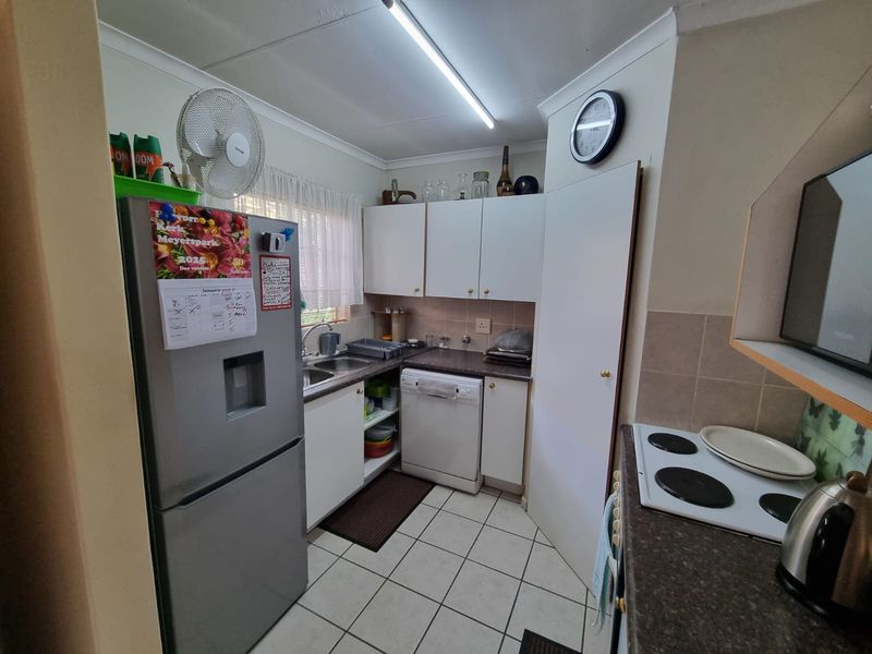 Compact kitchen featuring white cabinetry, laminate countertops, tiled flooring, and a functional layout with integrated electric hob and sink area.