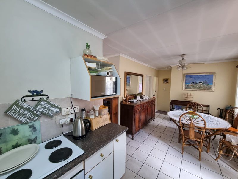 Open-plan kitchen and dining area featuring tiled flooring, a built-in electric hob, and a ceiling fan, offering a functional layout for daily living.