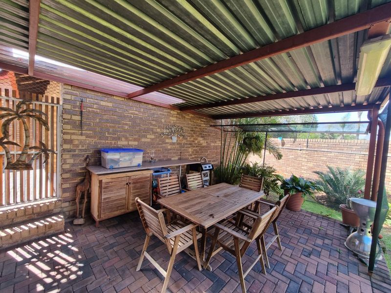 A covered outdoor patio area featuring brick paving, an exposed brick wall, and a built-in counter, providing a functional space for outdoor dining and relaxation.