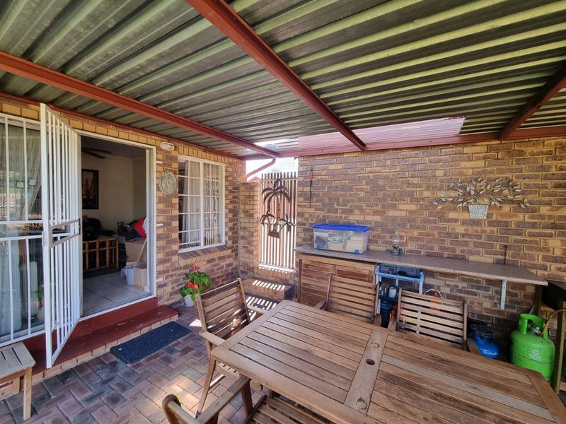 A covered outdoor patio featuring brick walls, a built-in counter, and paved flooring, providing a functional space for outdoor dining and relaxation.