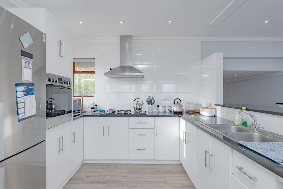 Modern kitchen featuring white cabinetry, granite countertops, stainless steel appliances, gas hob, and a subway tile backsplash with recessed lighting.
