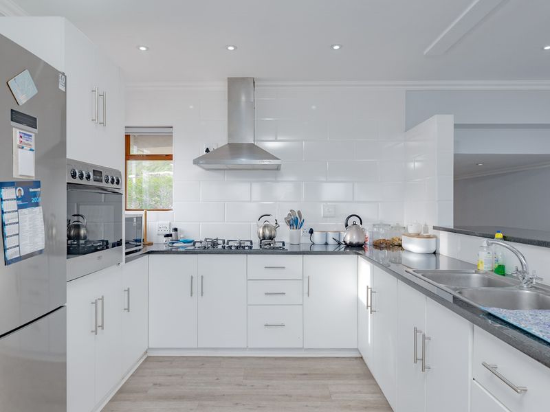 Modern kitchen featuring white cabinetry, granite countertops, stainless steel appliances, gas hob, and a subway tile backsplash with recessed lighting.
