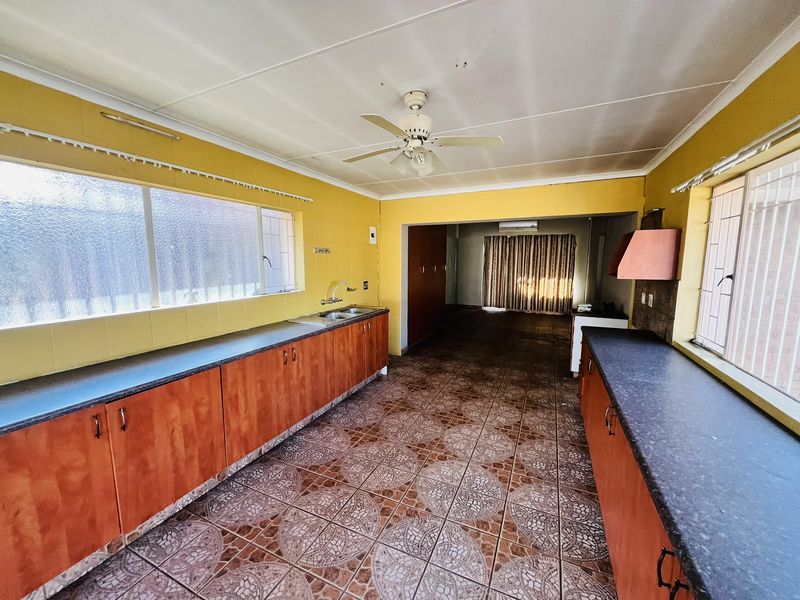 Spacious kitchen featuring extensive laminate cabinetry, double bowl sink, and tiled flooring, offering a functional layout ready for modern updates.