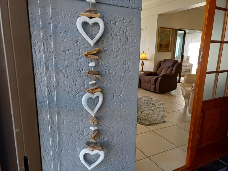 View from a textured wall entryway into a tiled living area featuring a timber framed door.