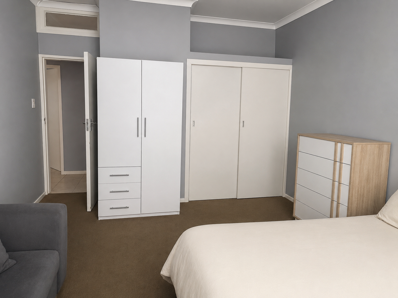 A well-maintained bedroom featuring neutral grey walls, carpeted flooring, and a built-in sliding door wardrobe providing ample storage space.