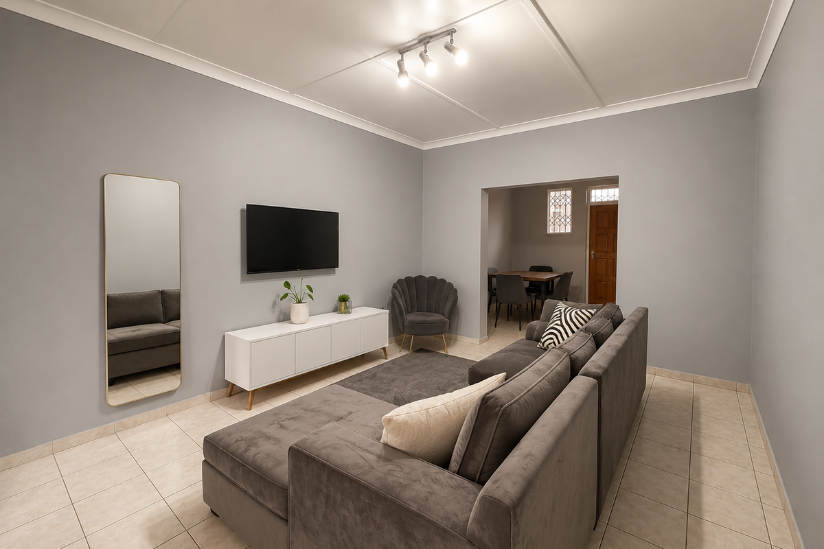 A well-maintained living room featuring neutral grey walls, tiled flooring, and a modern ceiling panel design with integrated track lighting.