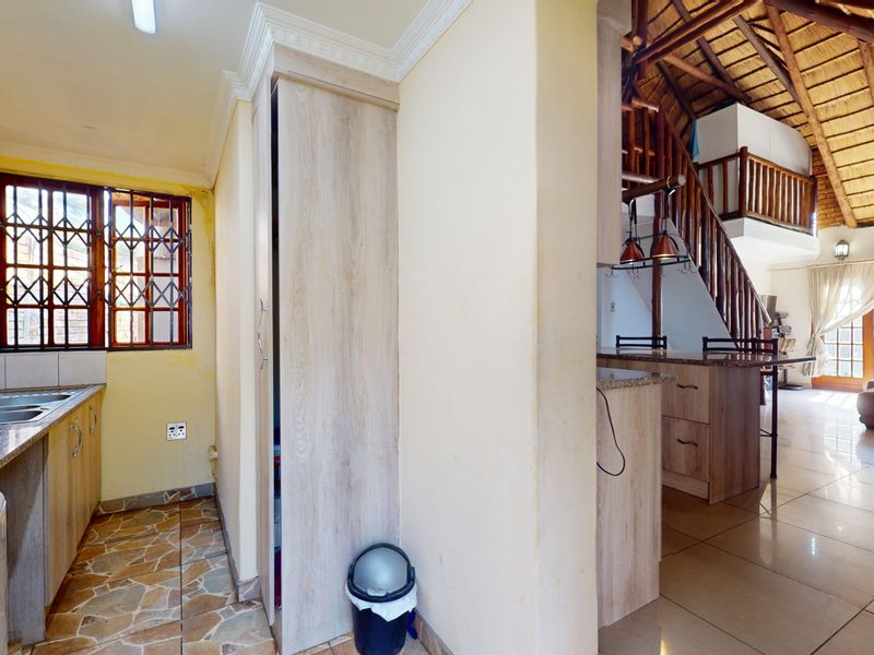 Open-plan kitchen and living area featuring a breakfast bar, tiled flooring, and a unique mezzanine level with a thatched roof ceiling.