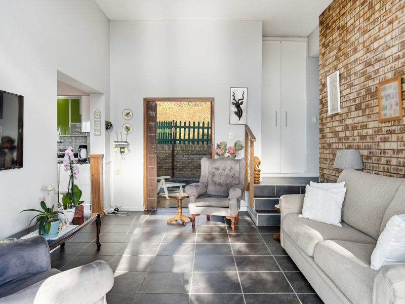 Spacious living area featuring an exposed brick wall, tiled flooring, and direct access to an outdoor patio space.
