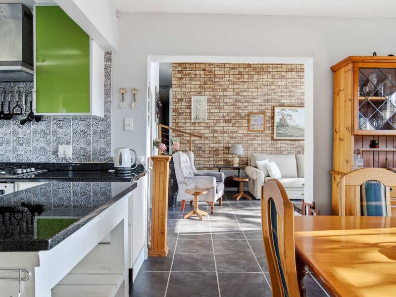 Open plan kitchen and living area featuring granite countertops, a modern extractor fan, and a distinctive exposed brick feature wall.