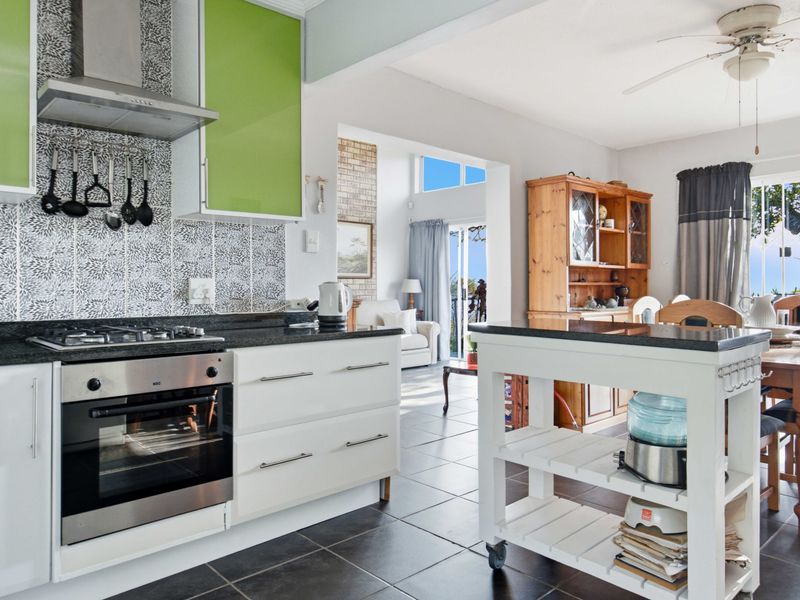 Open-plan kitchen and dining area featuring modern cabinetry, granite countertops, gas hob, and tiled flooring with direct access to an outdoor space.