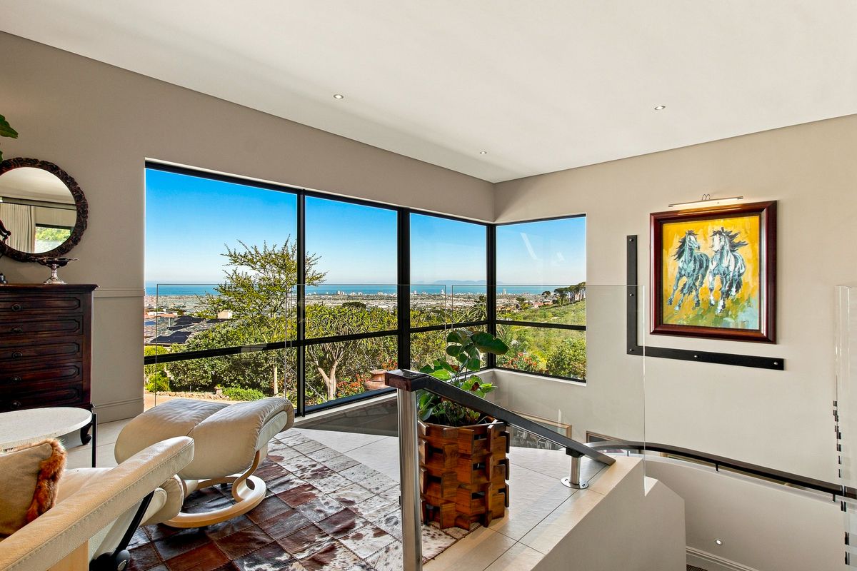 Bright living area featuring expansive floor-to-ceiling windows with panoramic coastal views, modern glass balustrades, and high-quality tiled flooring.