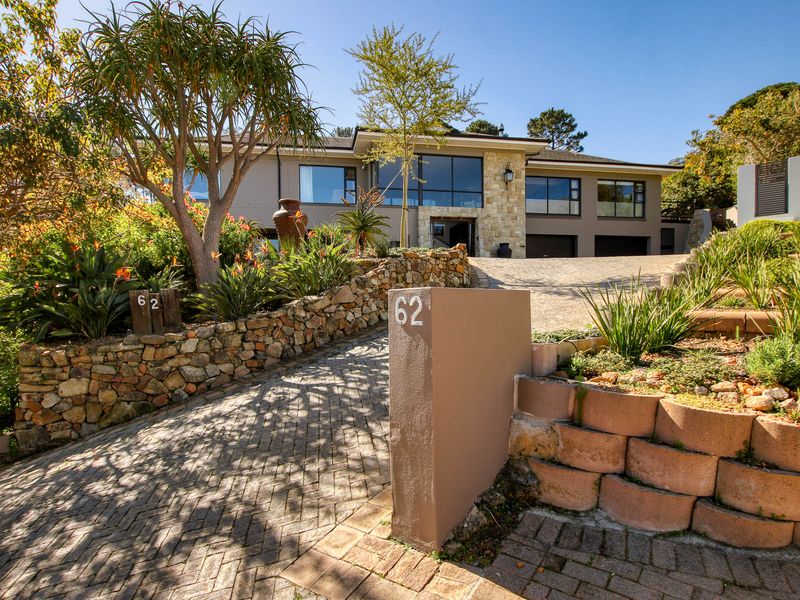 A well-maintained front elevation featuring a stone-clad facade, paved driveway, and landscaped terraced gardens leading to a double garage.