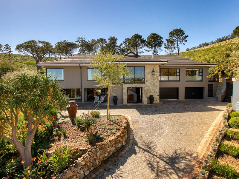 A well-maintained double-story residence featuring stone cladding, a paved driveway, and a double garage, set against a scenic hillside backdrop.