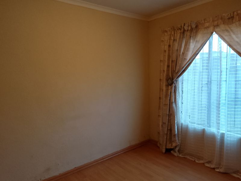 An empty bedroom featuring laminate flooring and neutral walls, ready for personalization or staging.