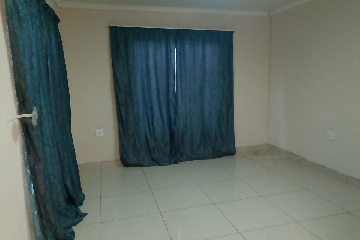 An empty bedroom featuring neutral tiled flooring and plain walls, ready for personalization.