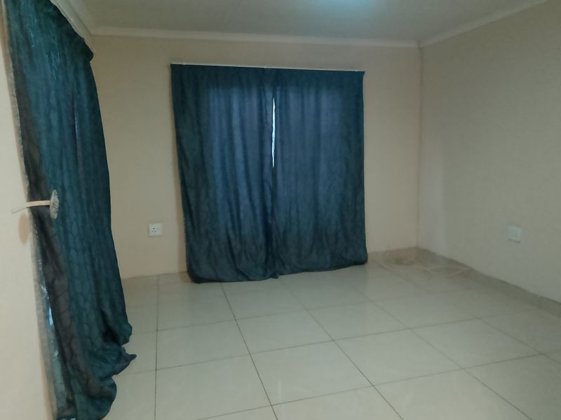 An empty bedroom featuring neutral tiled flooring and plain walls, ready for personalization.