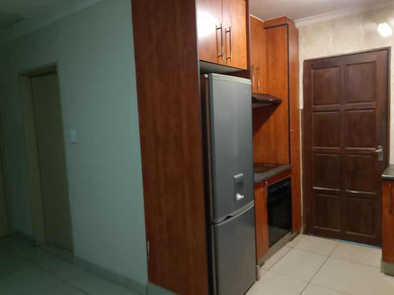 A compact kitchen featuring wood-finish cabinetry, built-in oven and hob, and tiled flooring, providing a functional workspace.