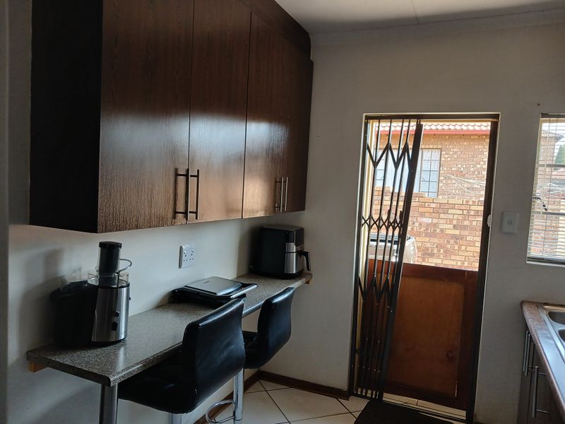 A functional kitchen area featuring dark wood-look cabinetry, a breakfast bar counter, and direct access to the exterior via a security gate.