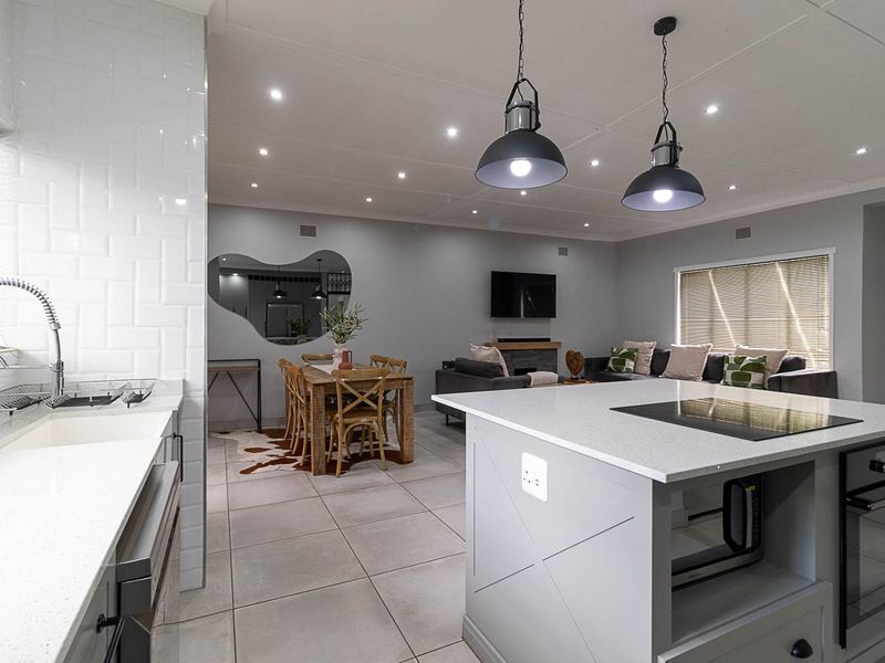 Modern open-plan living area featuring a sleek kitchen with quartz island, built-in appliances, subway tile backsplash, and integrated dining and lounge spaces.