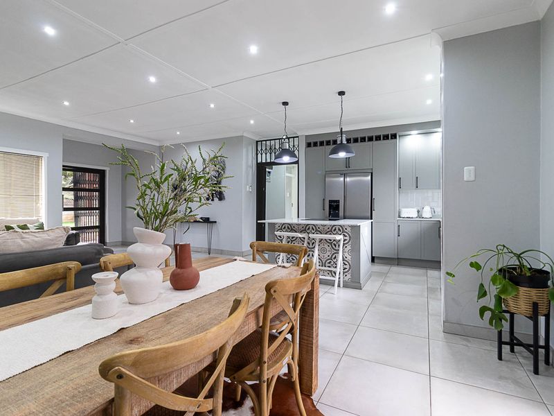 Modern open-plan living and dining area featuring a contemporary kitchen with a decorative island, tiled floors, and recessed lighting throughout.