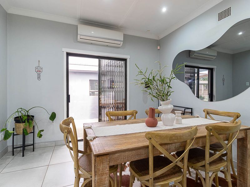 A bright dining area featuring tiled flooring, a split-system air conditioner, and a sliding glass door providing access to the exterior.