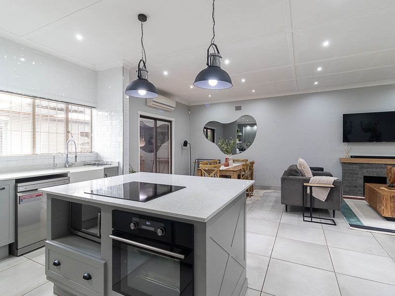 Modern open-plan living area featuring a well-appointed kitchen with a central island, built-in appliances, and a cozy lounge space with a fireplace.