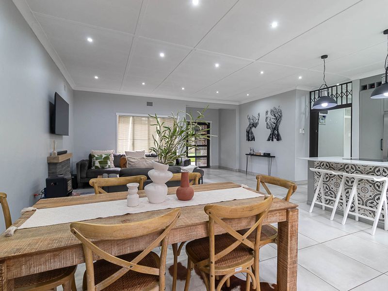 Spacious open-plan living and dining area featuring modern tiled floors, recessed lighting, and a stylish kitchen island with decorative tiling.