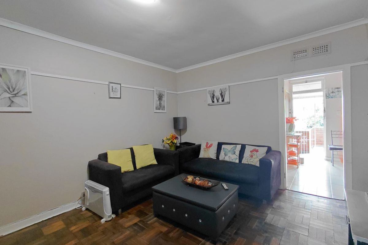 A living room featuring classic parquet flooring, a picture rail, and a doorway leading to an adjacent outdoor area.