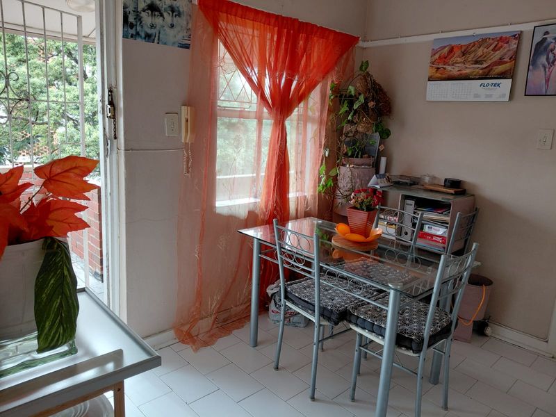 A dining area featuring tiled flooring, an intercom system, and direct access to an outdoor space through a security gate.