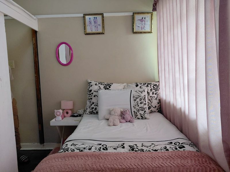 A compact bedroom featuring neutral wall tones and floor-to-ceiling curtains, requiring minor cosmetic updates to the door frame and wall finishes.