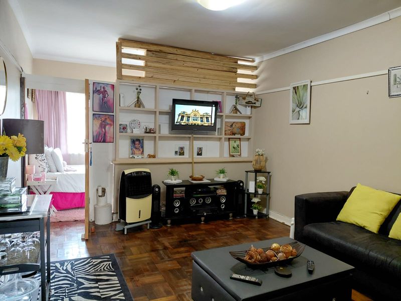 A living room featuring classic parquet flooring, a built-in wooden shelving unit, and a picture rail, offering a warm and functional living space.