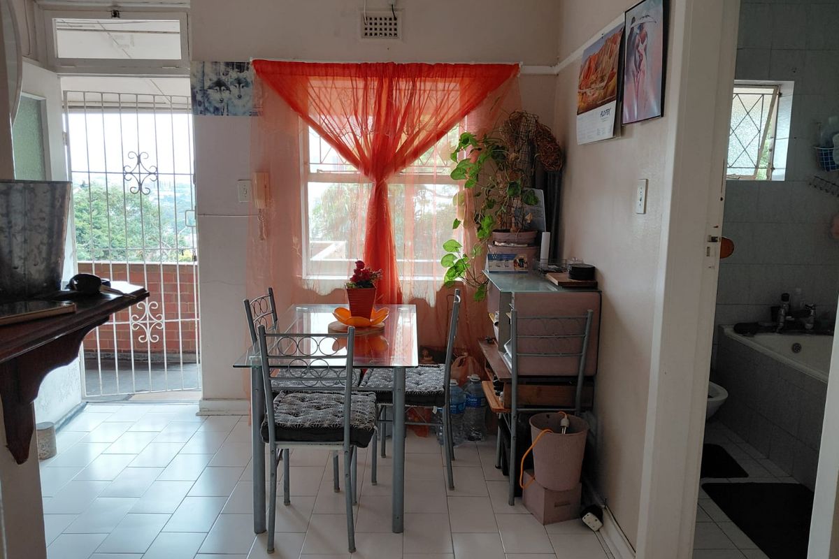 A compact dining area featuring tiled flooring and direct access to an outdoor balcony through a security gate.