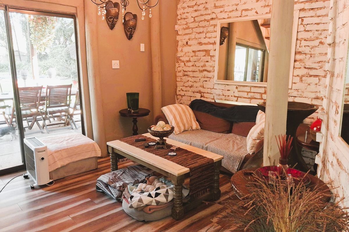 Cozy living room featuring an exposed brick feature wall, laminate flooring, and a sliding glass door providing access to the outdoor patio area.