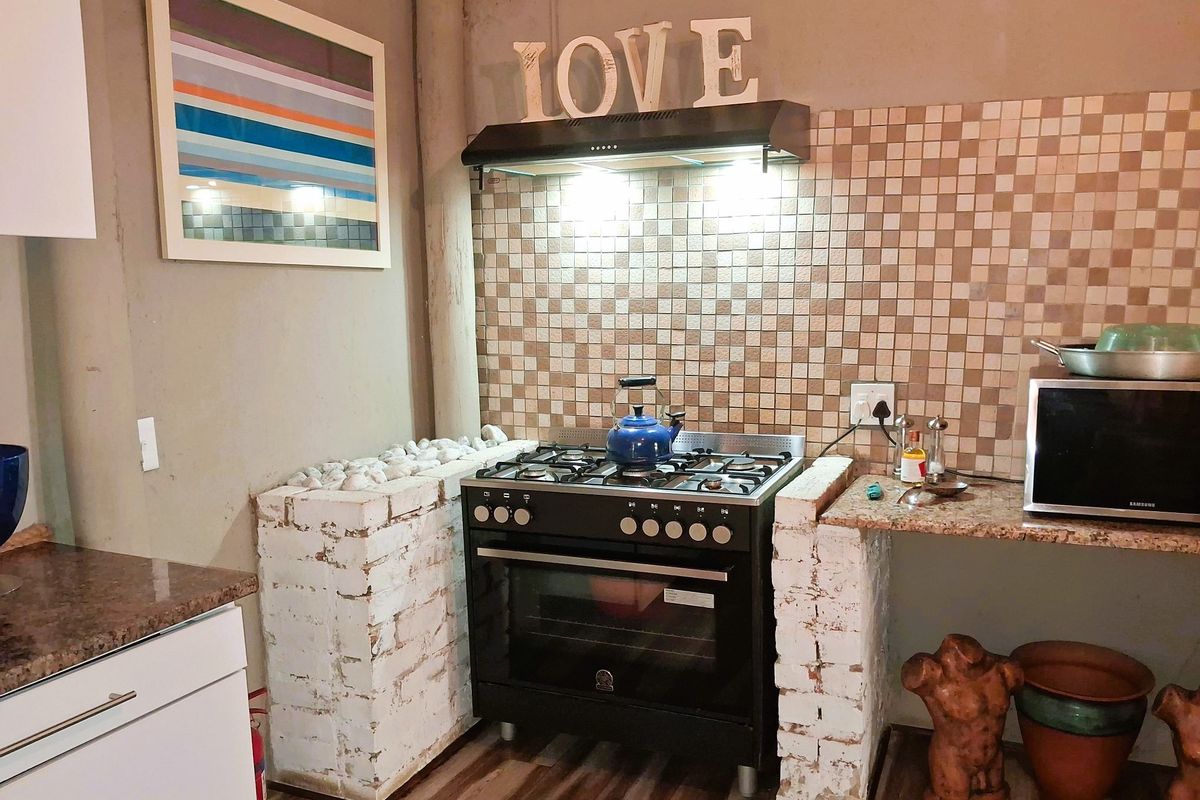 Kitchen area featuring a gas stove with extractor fan, tiled backsplash, and unique brick-based granite countertops.