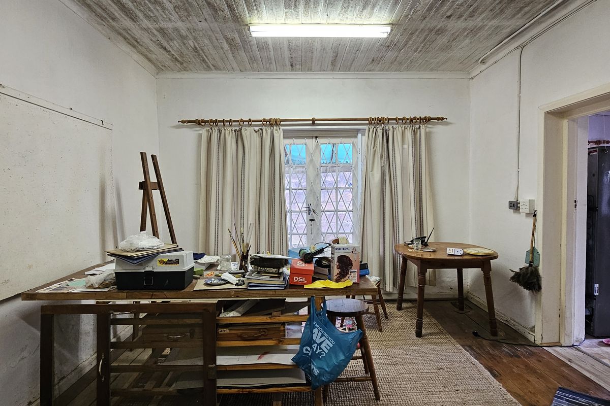 A living area featuring timber ceilings, hardwood floors, and french doors leading to the exterior, requiring cosmetic updates to improve the overall finish.