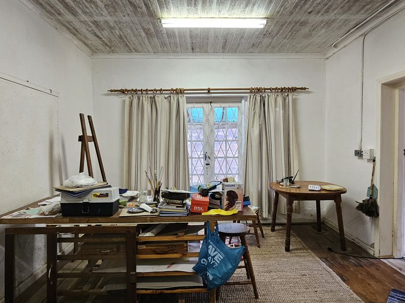 A living area featuring timber ceilings, hardwood floors, and french doors leading to the exterior, requiring cosmetic updates to improve the overall finish.