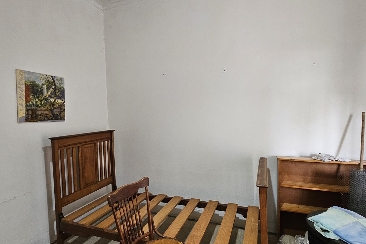 A bedroom space featuring plain walls with visible hairline cracks, providing a blank canvas for potential renovation or interior design updates.