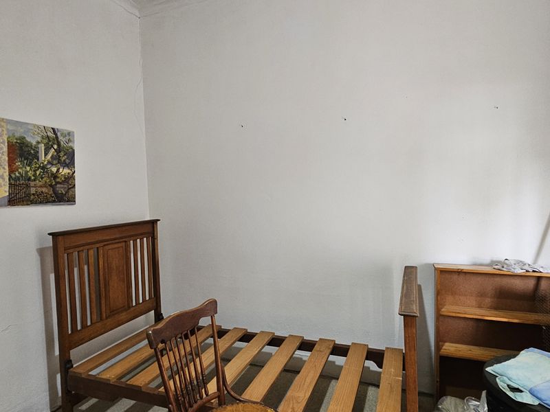 A bedroom space featuring plain walls with visible hairline cracks, providing a blank canvas for potential renovation or interior design updates.