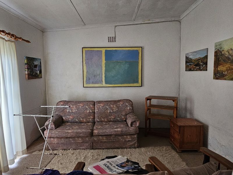 A living room space featuring basic finishes, including a ceiling vent and wall-mounted electrical outlets, requiring cosmetic updates to improve the overall condition.