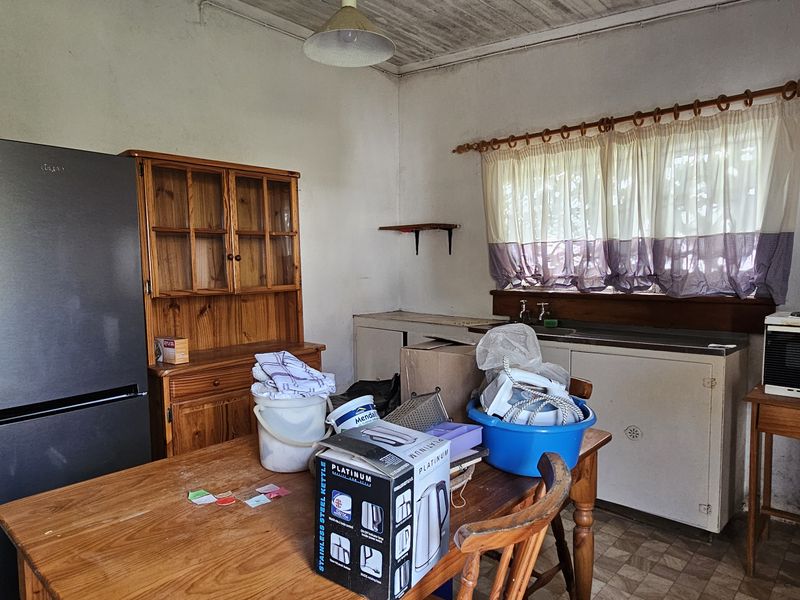 A dated kitchen area featuring a stainless steel sink, built-in cabinetry, and a timber ceiling, offering significant potential for modernization and renovation.