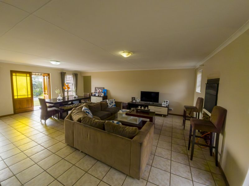 Spacious open-plan living and dining area featuring tiled flooring, a built-in fireplace, and direct access to the outdoors through a timber-framed glass door.