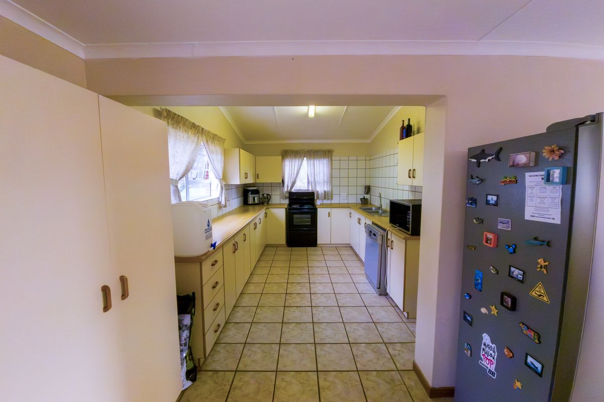 A functional kitchen featuring tiled flooring, ample built-in cabinetry, a tiled backsplash, and a double sink with integrated appliances.