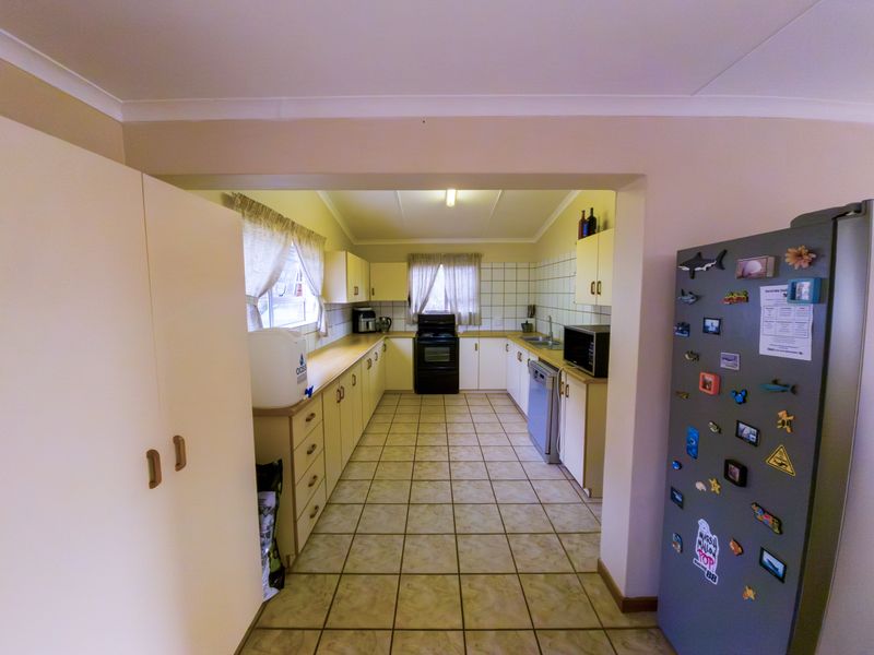 A functional kitchen featuring tiled flooring, ample built-in cabinetry, a tiled backsplash, and a double sink with integrated appliances.